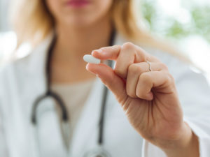 Frau mit Schmerzmittel Tablette in der Hand